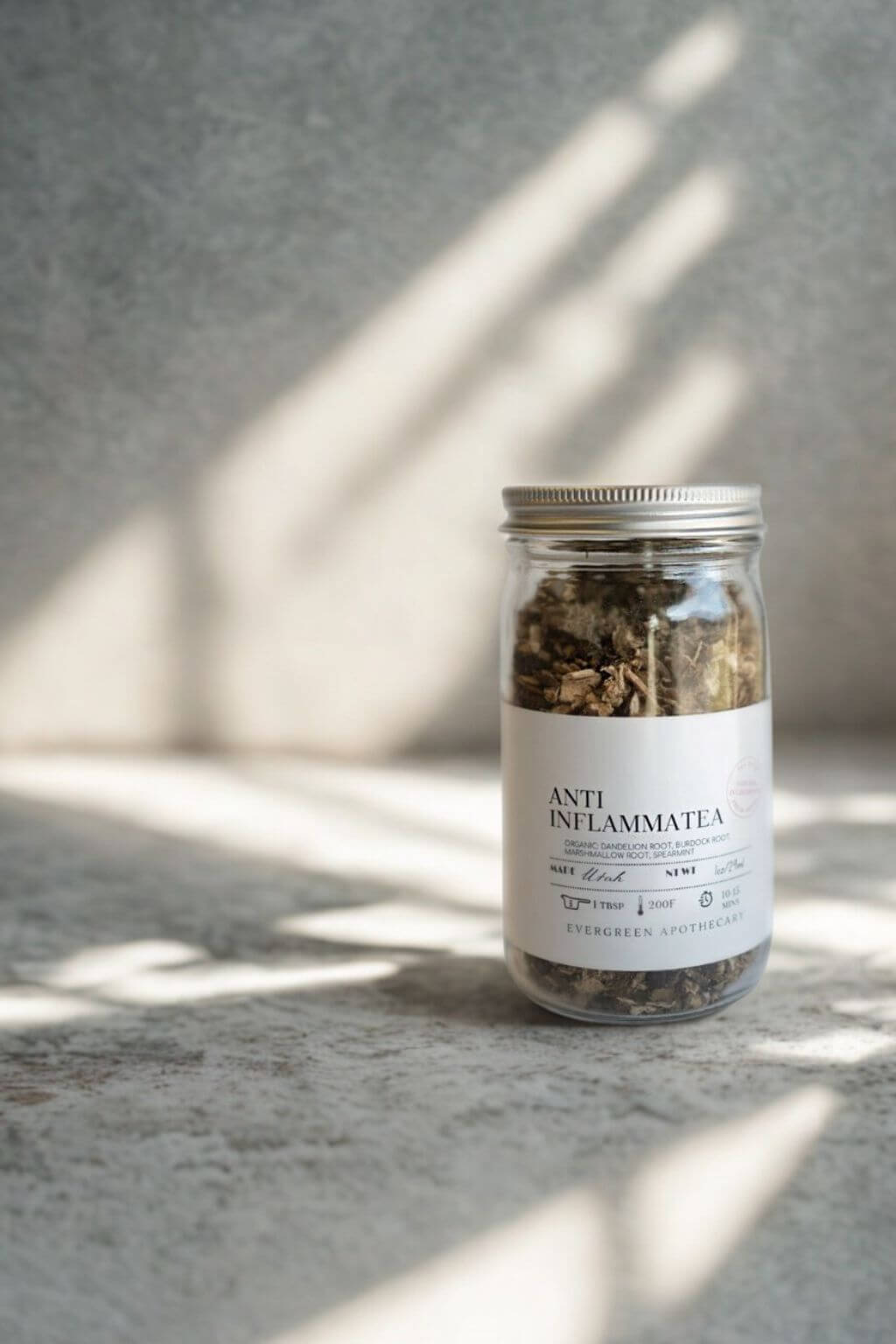 Evergreen Apothecary Anti-Inflammatea jar against stone background with soft sunlight