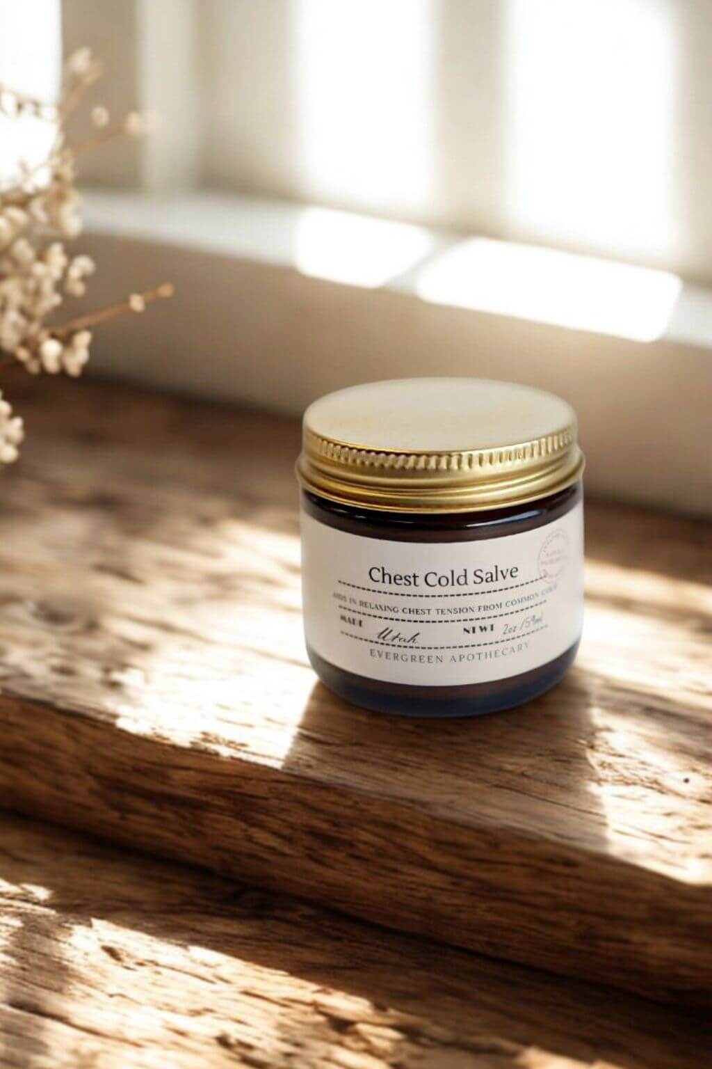 Evergreen Apothecary Chest Cold Salve jar on wooden surface in natural sunlight 