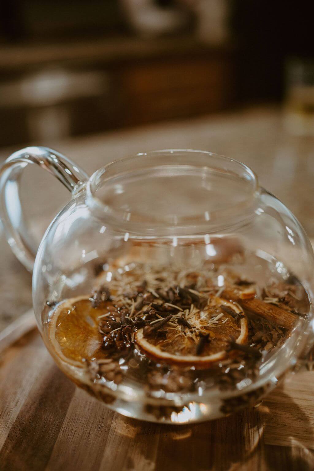 Glass teapot filled with simmering oranges, rosemary, and spices for Christmas simmer pot