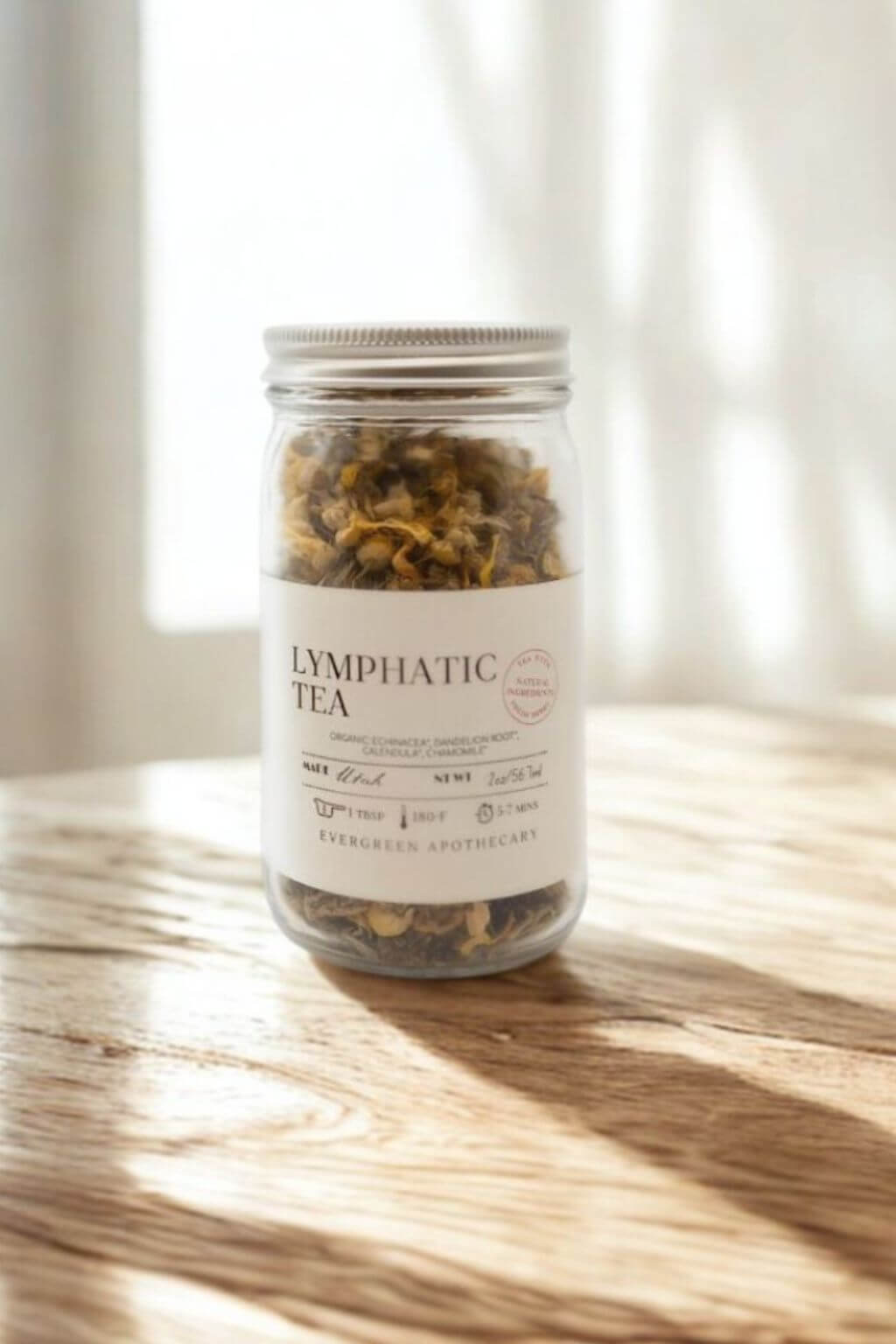 Glass jar of Evergreen Apothecary Lymphatic Tea on sunlit wooden table