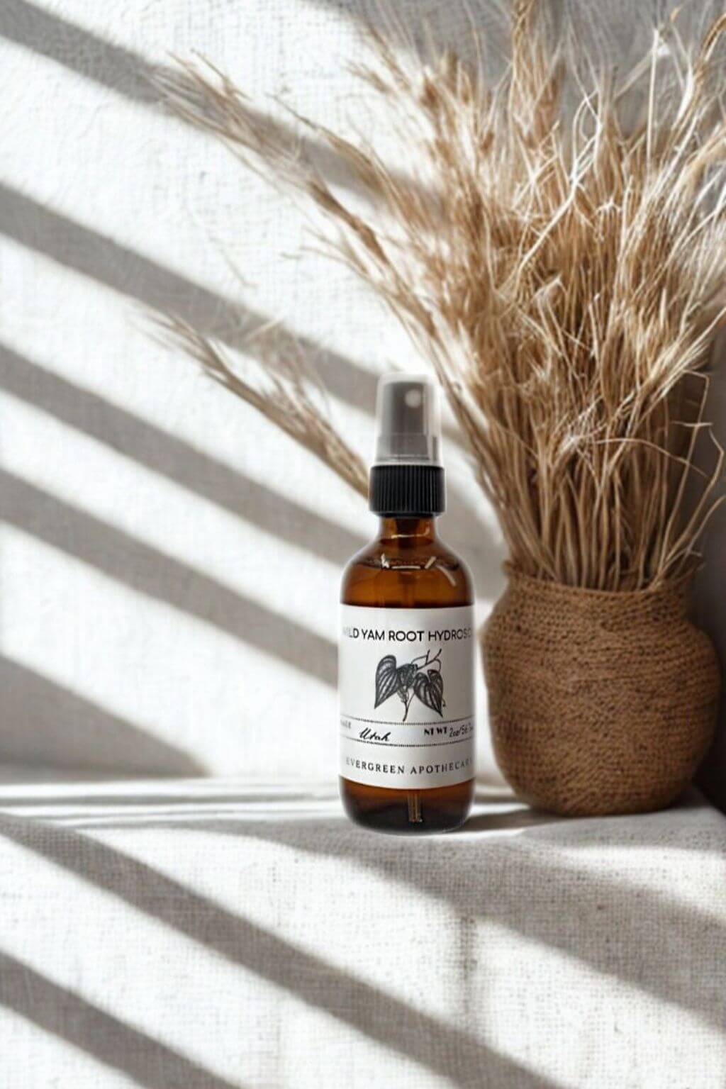 Wild Yam Root Hydrosol bottle styled with dried grasses in soft natural light