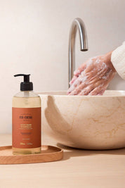 Hand washing with Fer à Cheval Orange Blossom Marseille Liquid Soap by marble sink.
