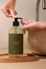 Person using a bottle of Fer a Cheval Marseille Liquid Soap on a wooden tray.