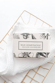 Wild Honeysuckle Shea butter moisturizing soap styled in a wire basket with linens.