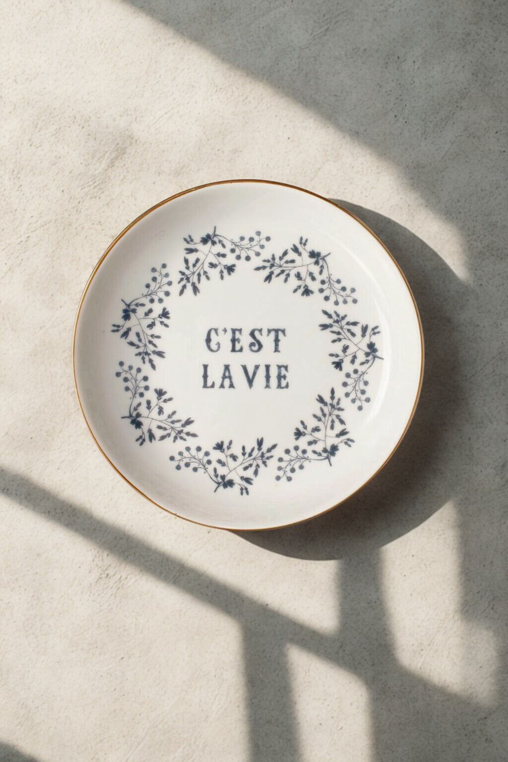 Decorative plate with floral design and 'C'est Lavie' text on a textured surface