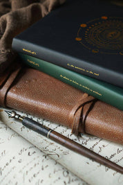 Magic of I 2026 Astrological Planners in Black and Green stacked upon an old leather journal