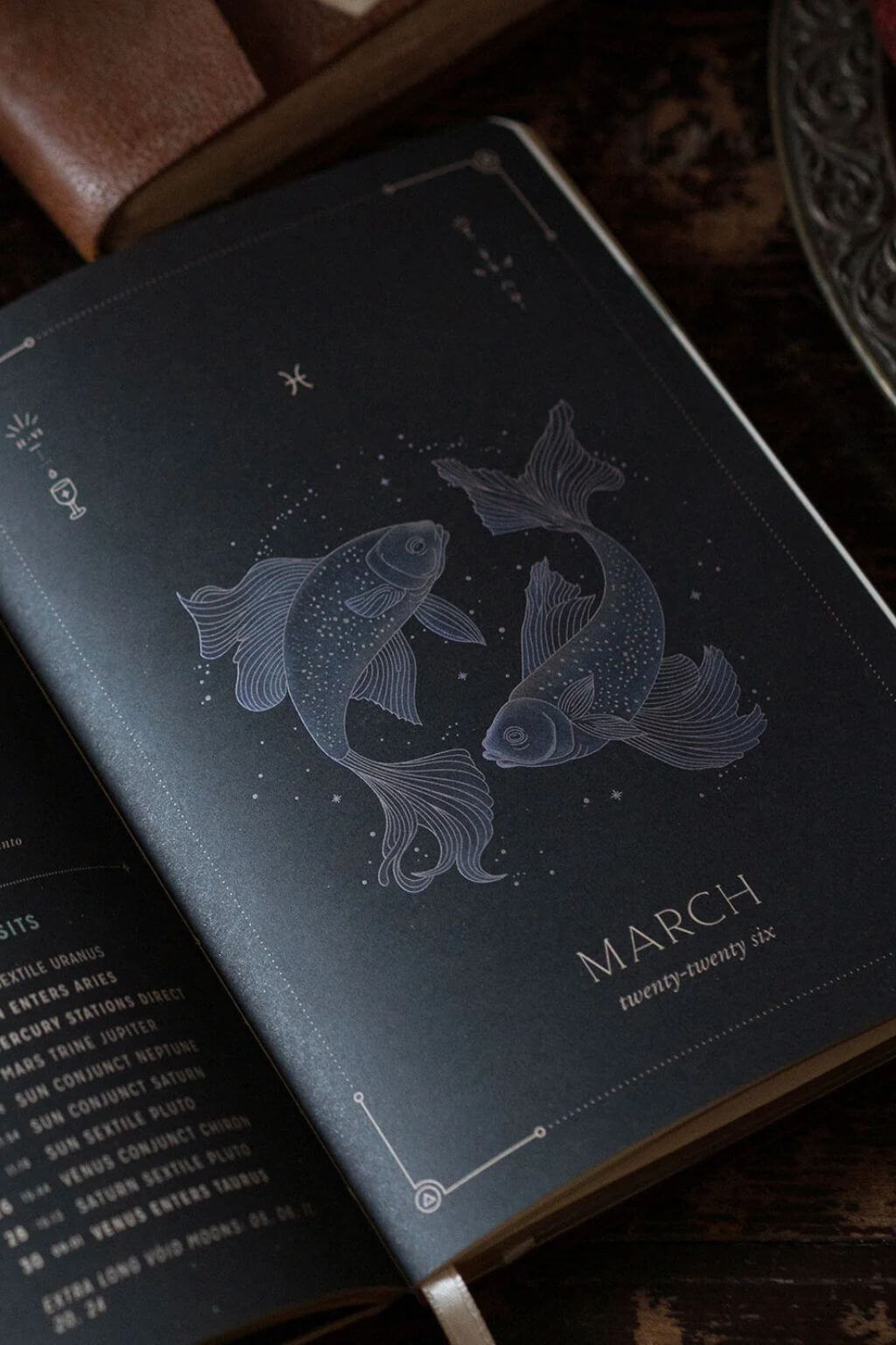 Dark interior astrology spread featuring Pisces artwork and March 2026 calendar