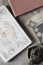 Close-up of gold-foil celestial artwork on white Magic of I planner cover