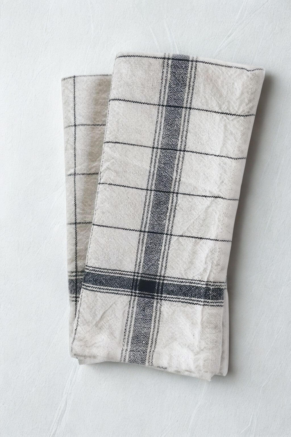 Handwoven French stripe kitchen towel in navy blue and off-white, folded on light linen background.