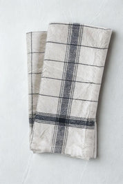Handwoven French stripe kitchen towel in navy blue and off-white, folded on light linen background.