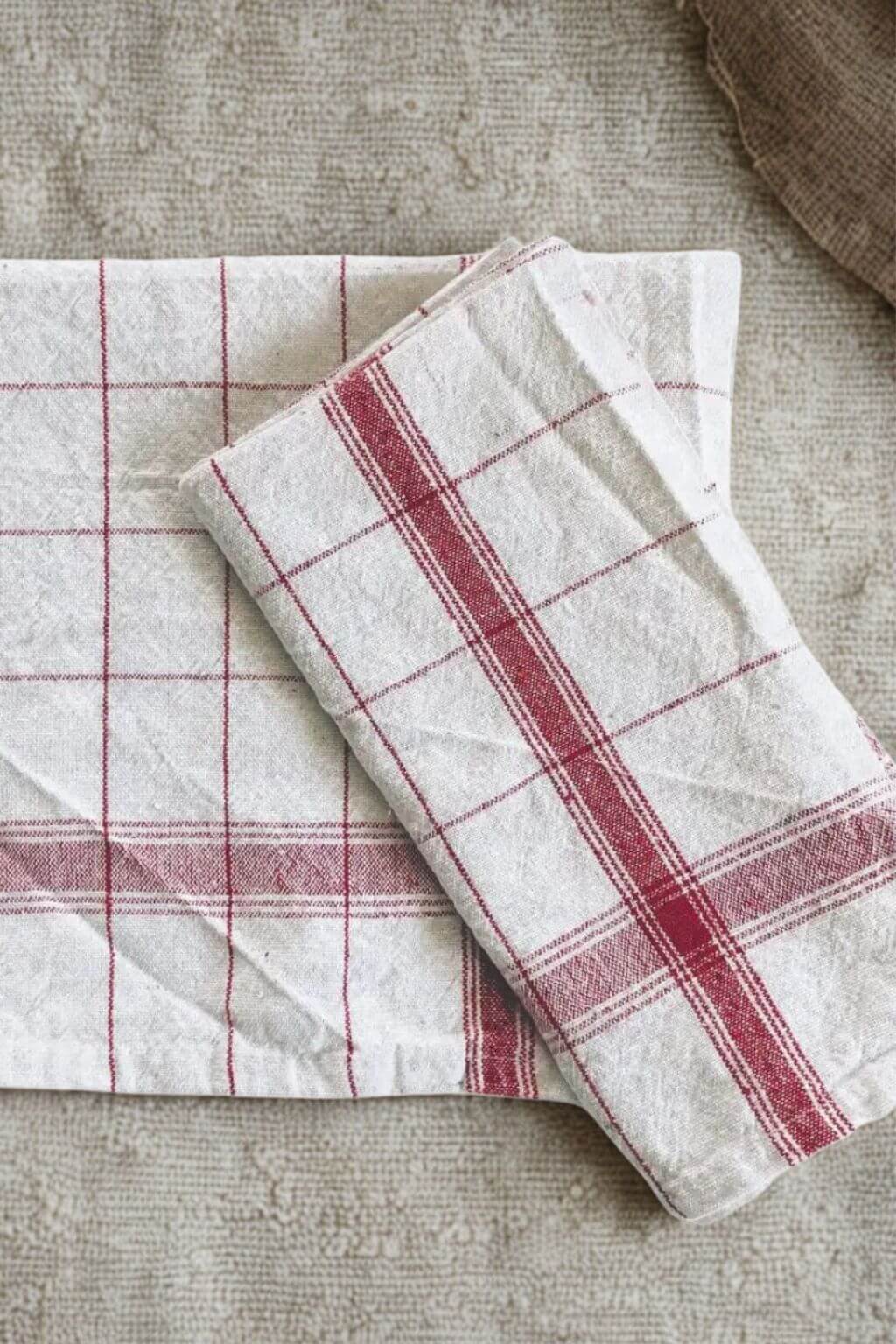 Handcrafted red and off-white French Stripe kitchen towel folded on rustic fabric surface.