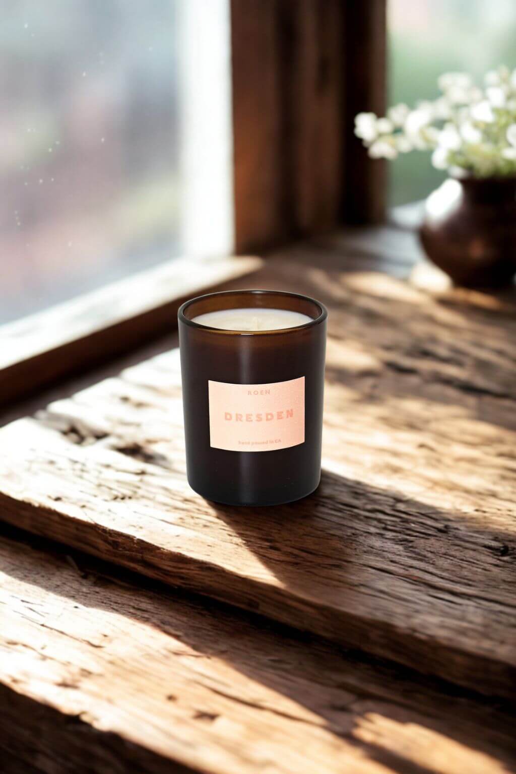 Amber glass Dresden candle on rustic wood near window