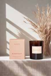 Roen Marmont candle in warm sunlight near a vase of dried grasses