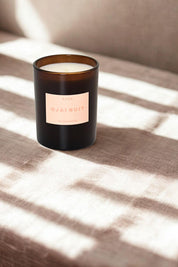 Candle resting on textured linen with soft window shadows