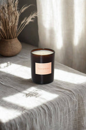 Topanga candle on a linen-draped table beside dried grasses