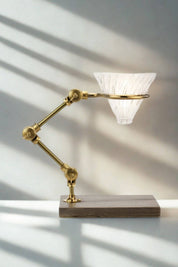 The Curator brass pour-over coffee stand with glass dripper on walnut base.